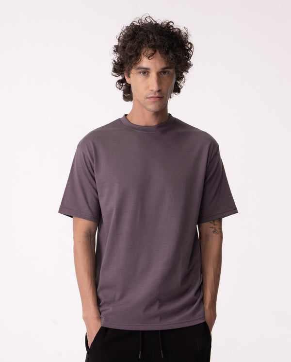 Man wearing a plain purple t-shirt against a white background