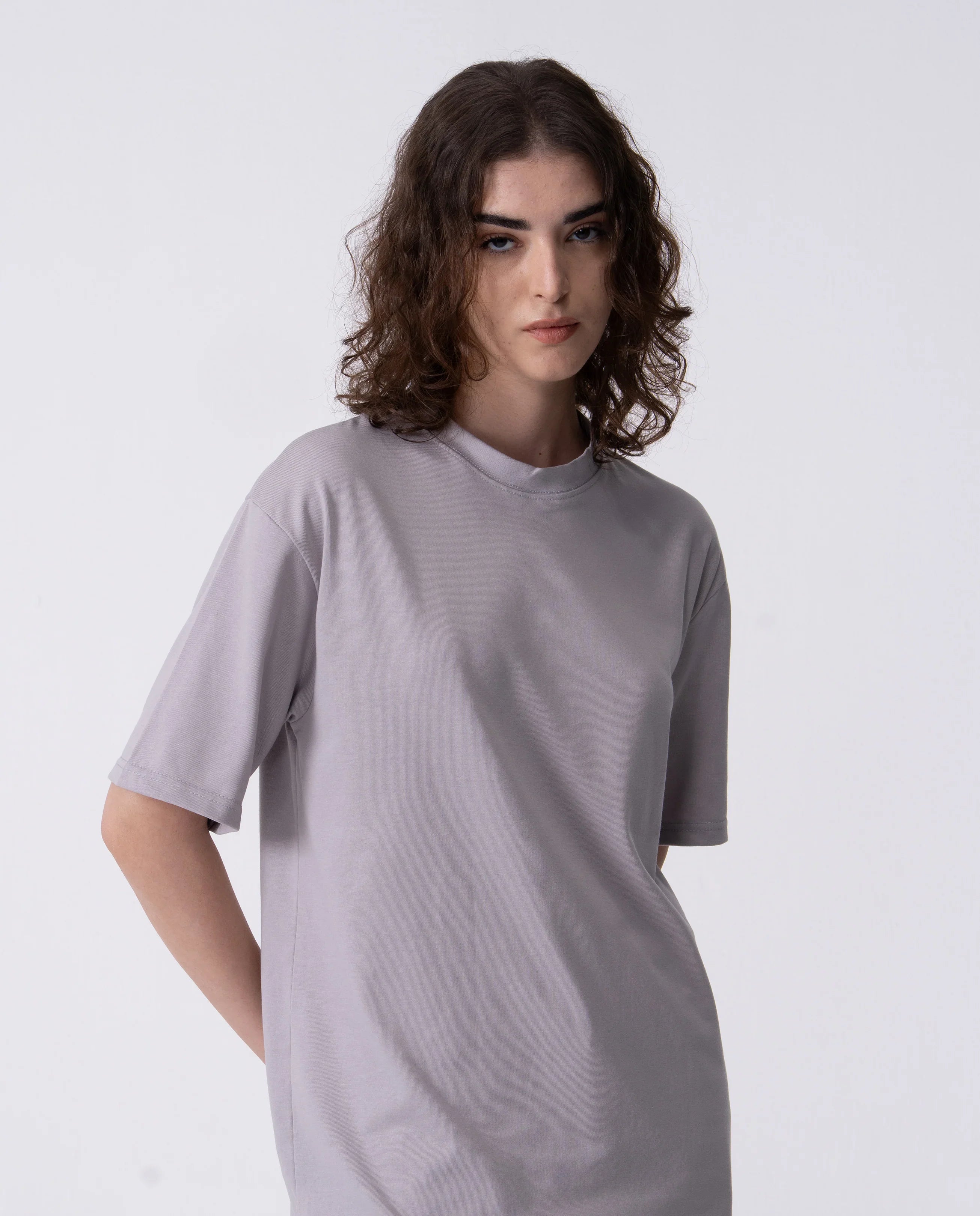 Person wearing a plain gray t-shirt against a white background