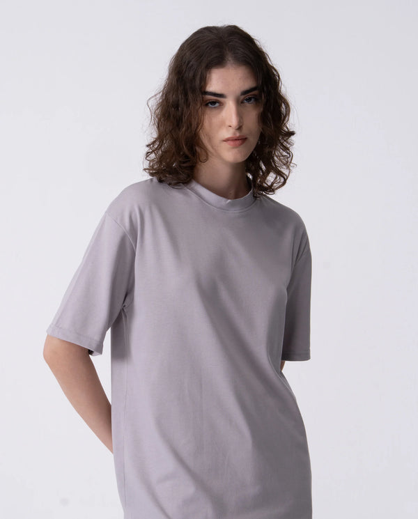 Person wearing a plain gray t-shirt against a white background