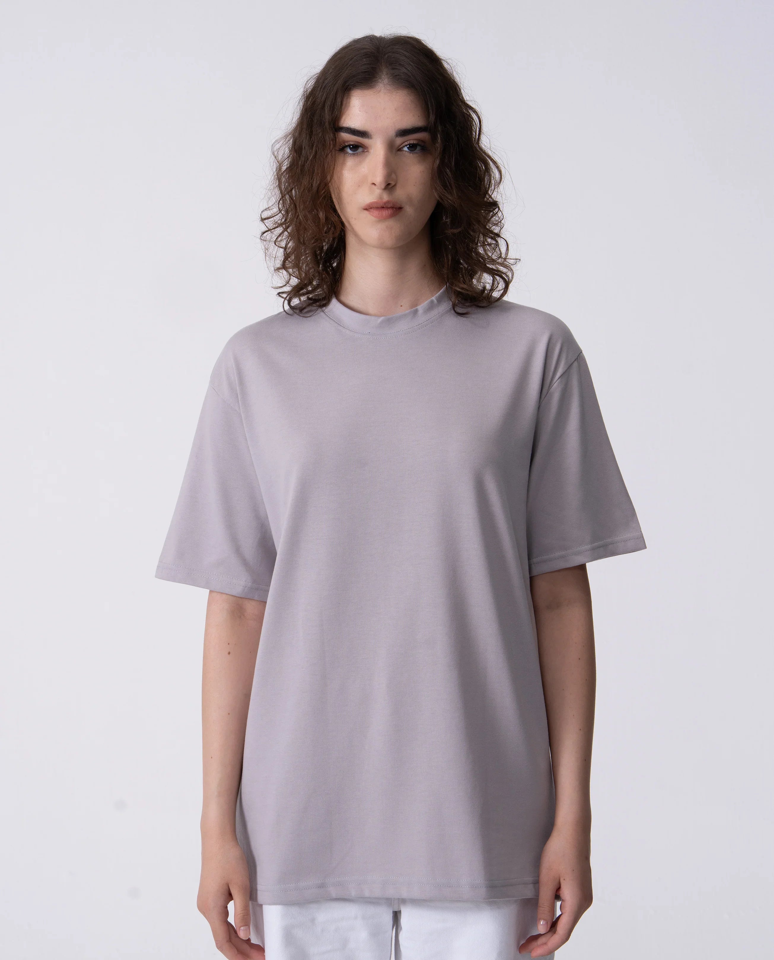 Person wearing a plain light gray t-shirt on a white background