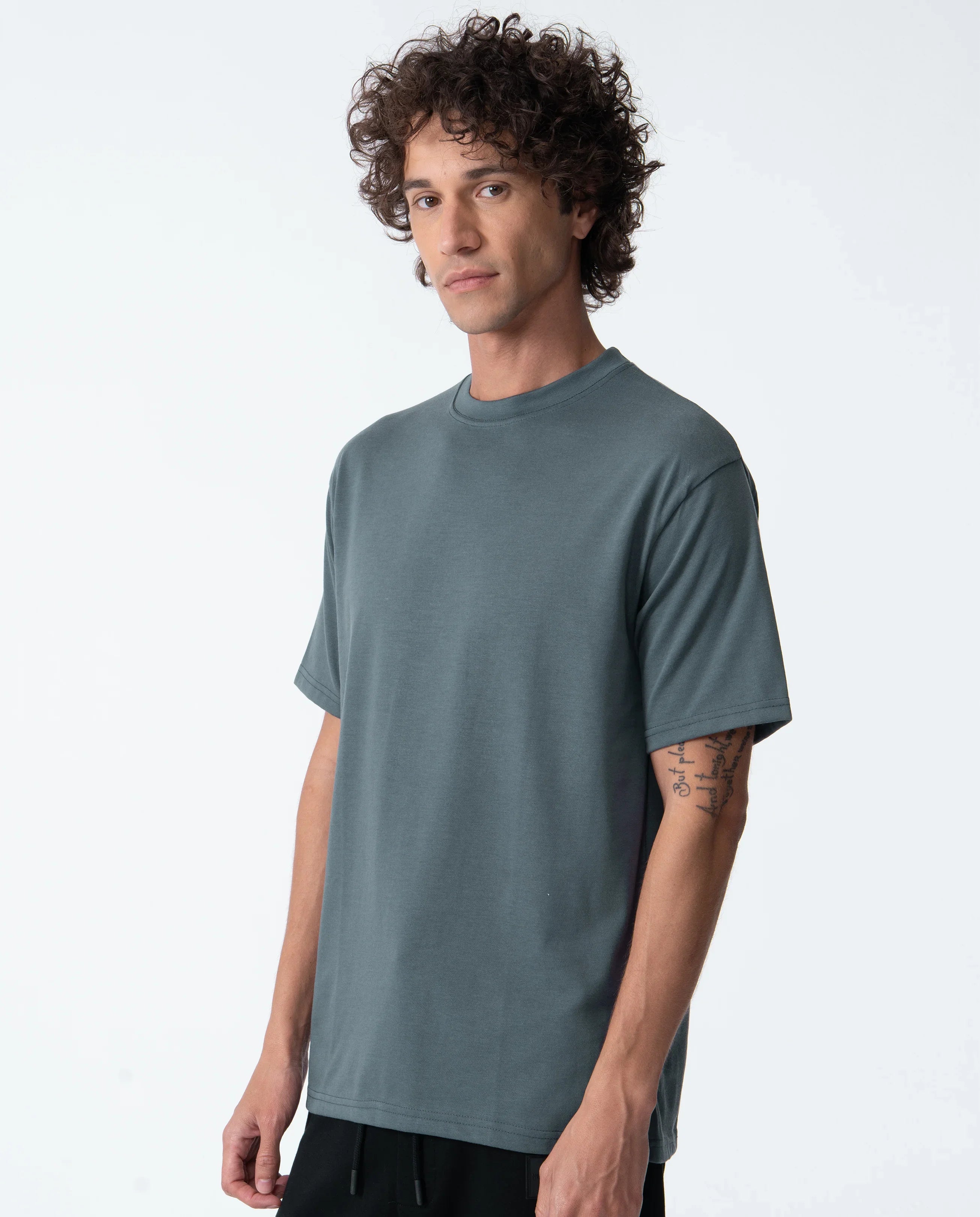 Man wearing a plain teal t-shirt against a white background