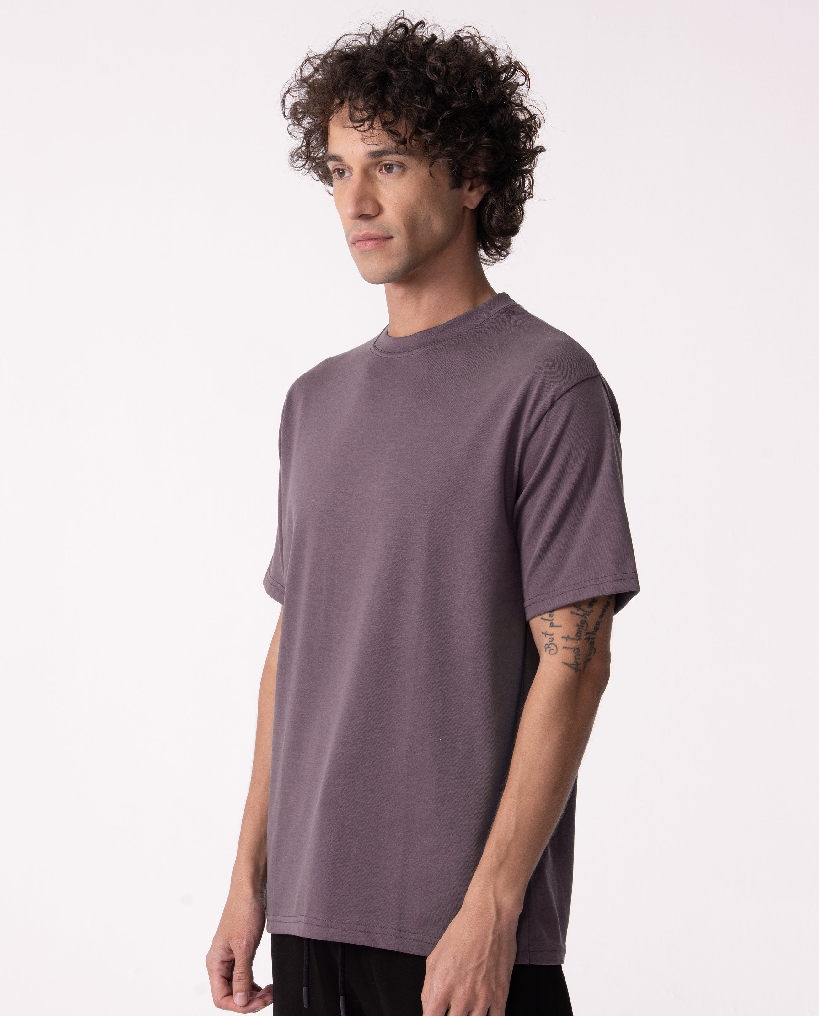 Man wearing a plain purple t-shirt on a white background