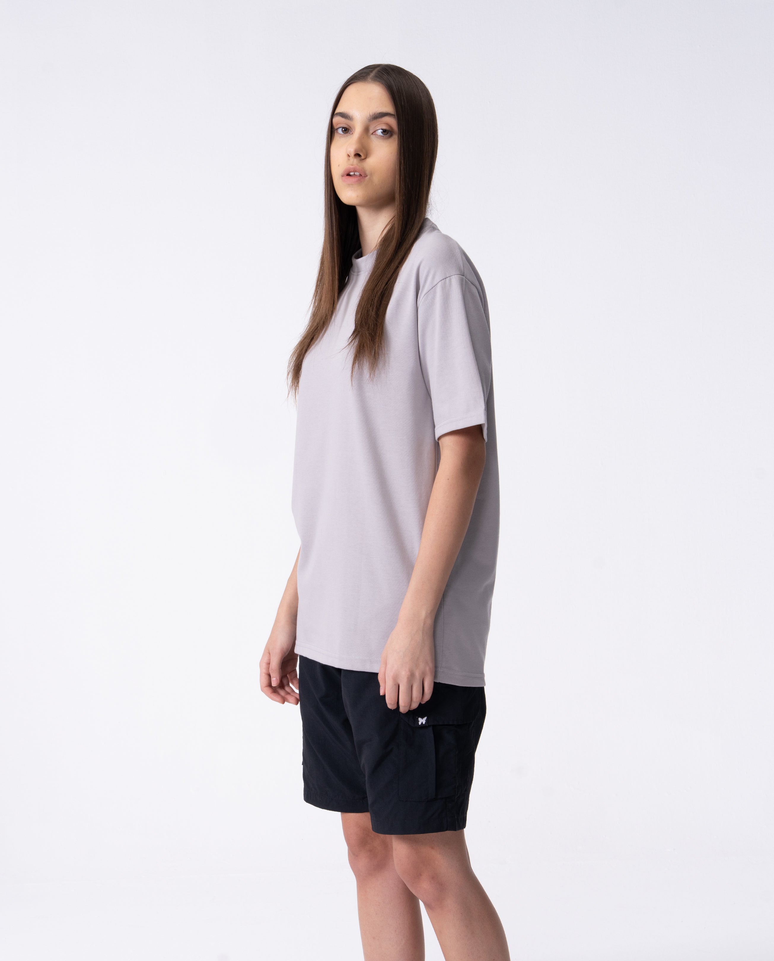 Woman wearing a light gray t-shirt and black shorts on a white background