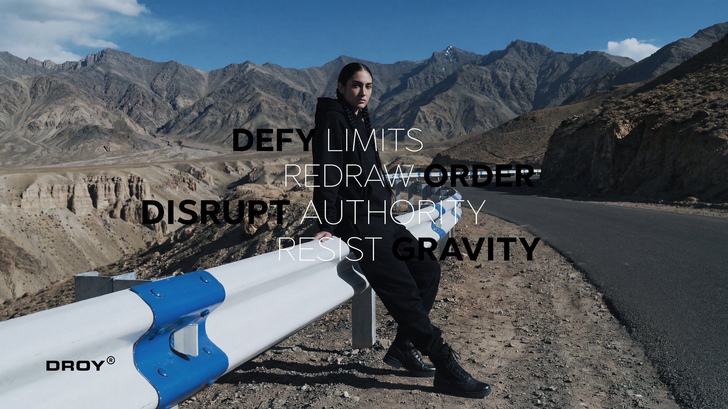 Person sitting on a road with mountains in the background, featuring motivational text and a brand logo.
