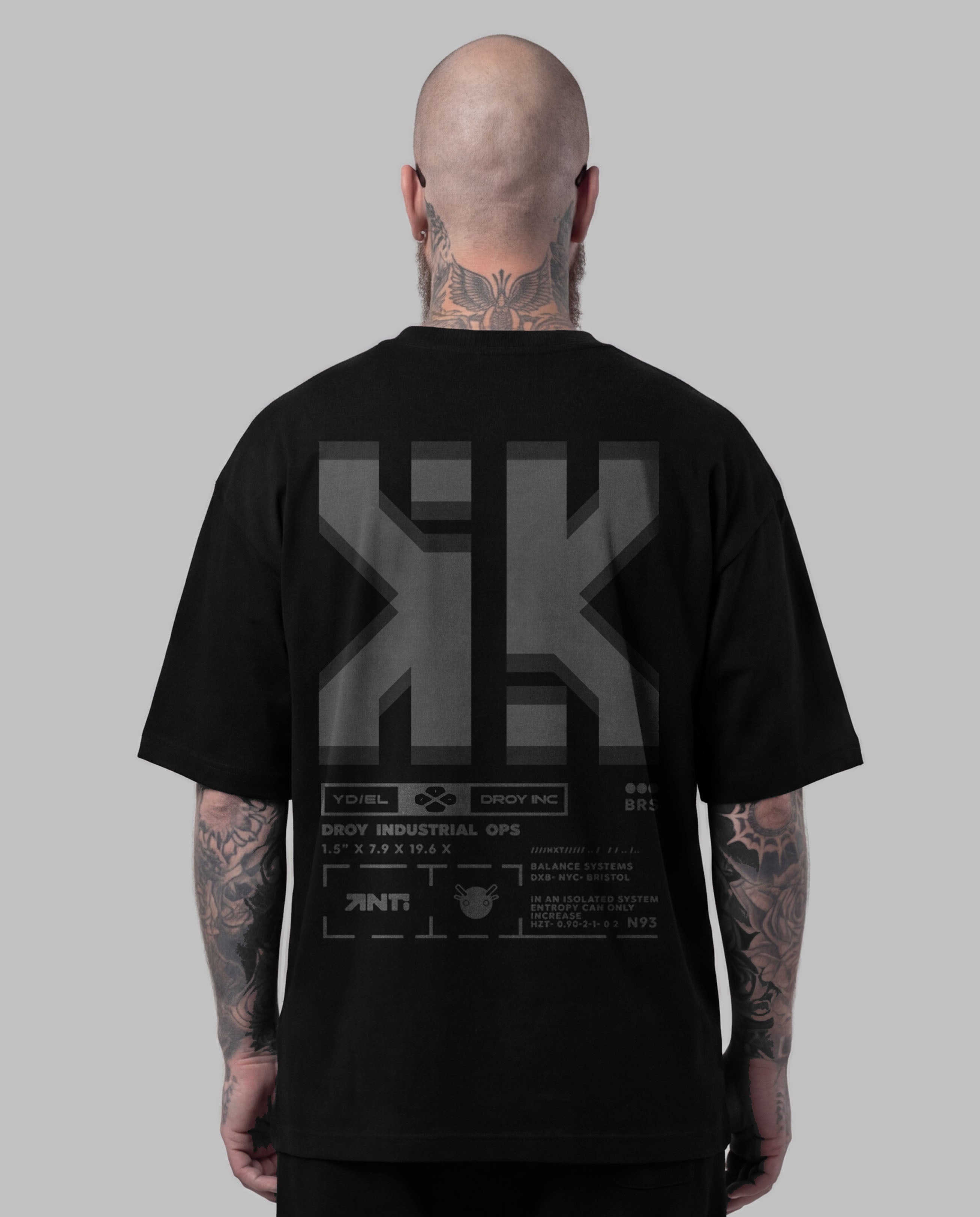 Person wearing a black t-shirt with a logo on the back against a gray background