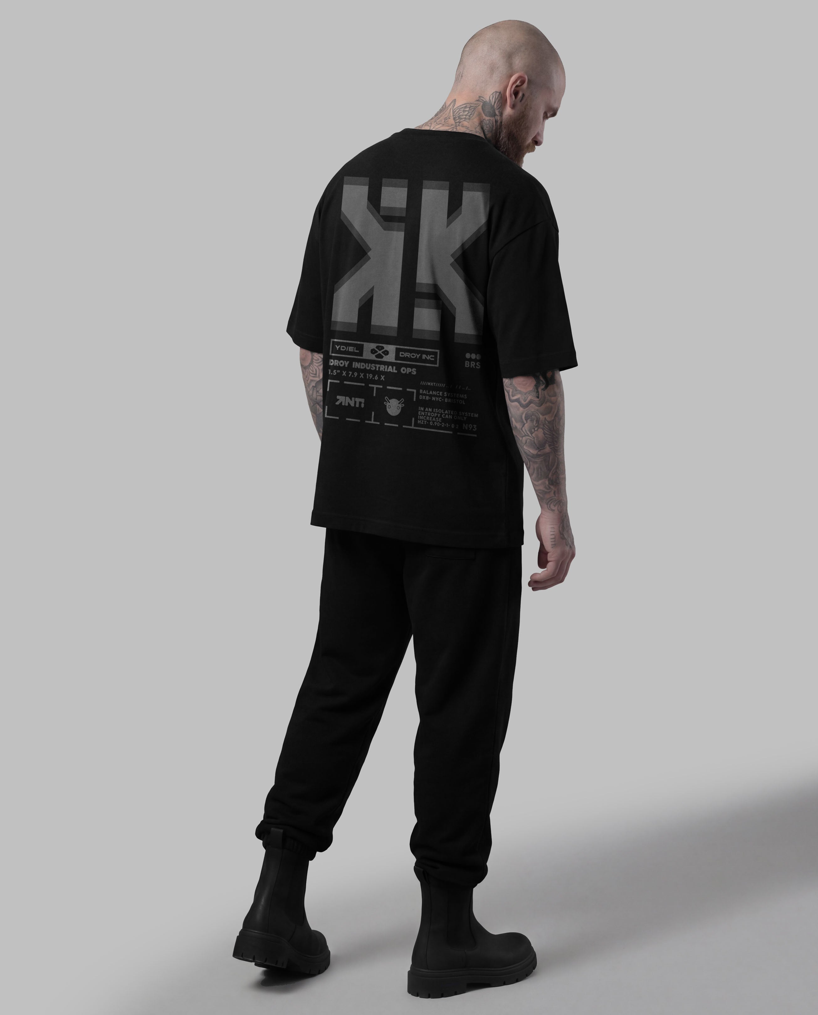 Person wearing a black t-shirt with a logo on the back against a gray background