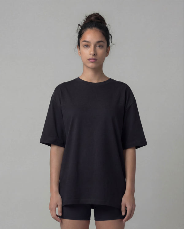 Person wearing a black oversized t-shirt against a plain background
