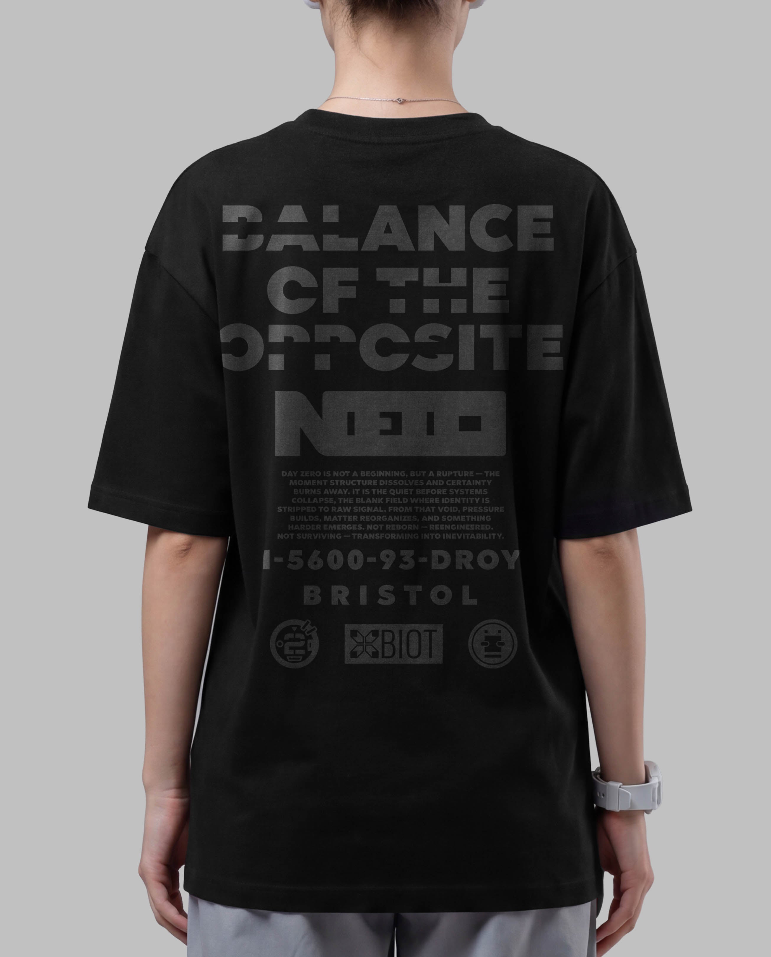 Person wearing a black t-shirt with text on the back against a gray background