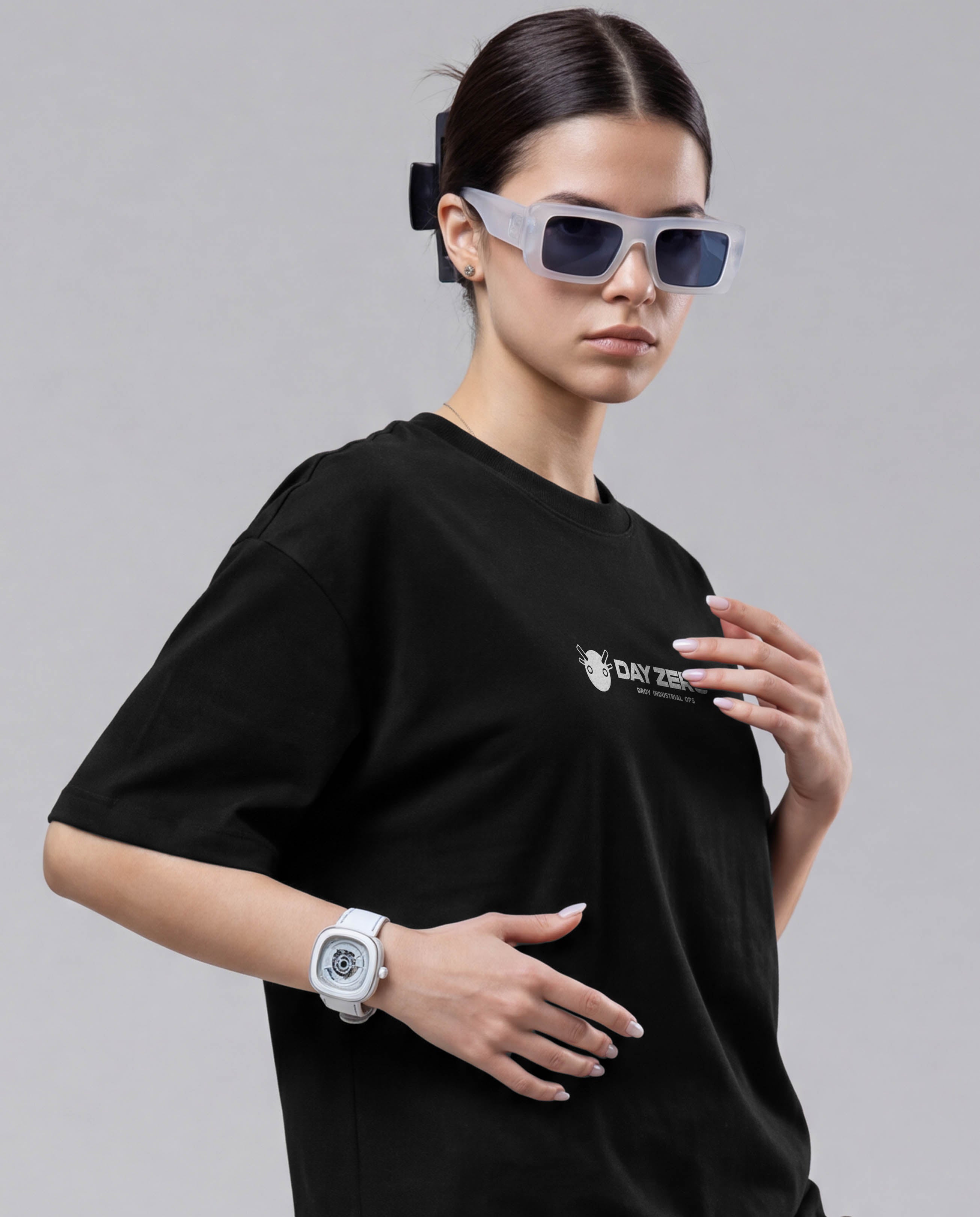 Person wearing a black t-shirt with a logo and futuristic sunglasses on a gray background