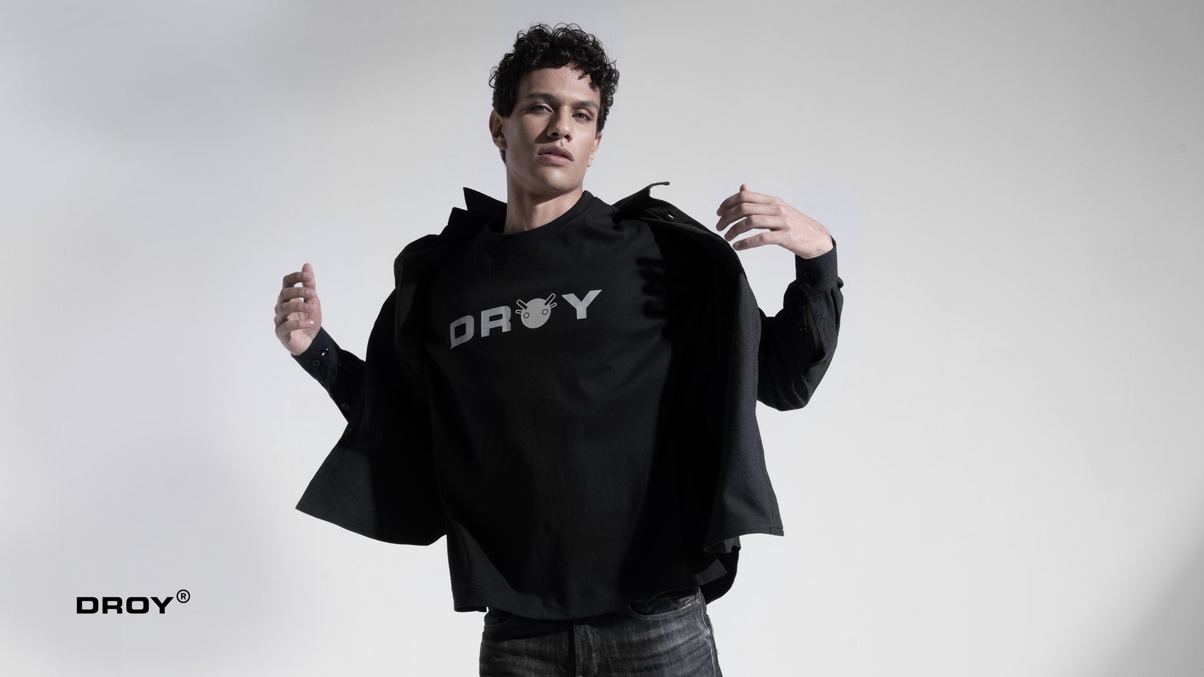 Person wearing a black hoodie with 'DROY' branding on a white background