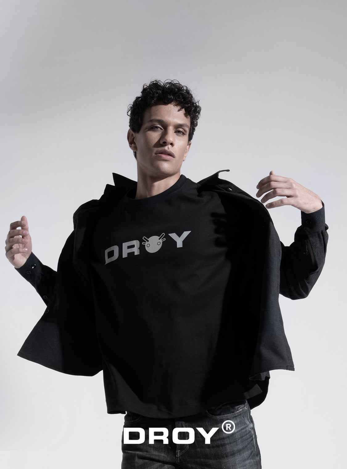 Person wearing a black hoodie with 'DROY' branding on a gray background