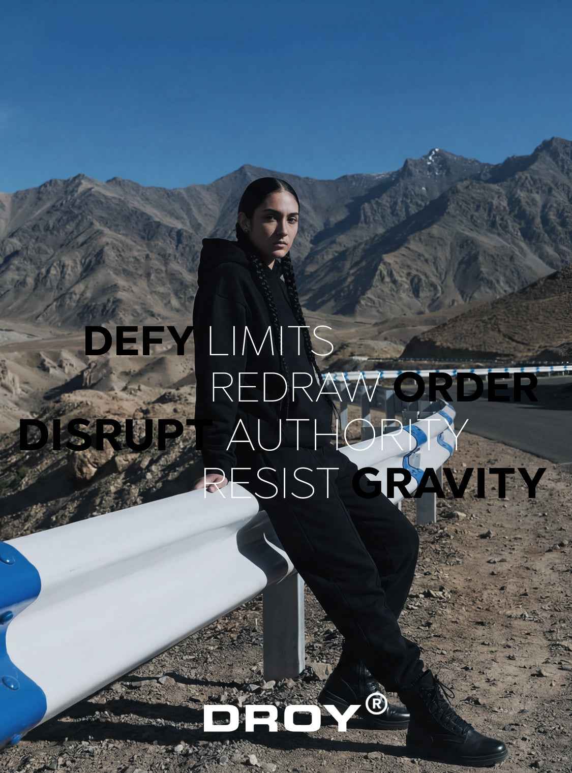 'DROY' Person sitting on a bench with mountains in the background, wearing black clothing and holding a surfboard. Text and brand name overlay.